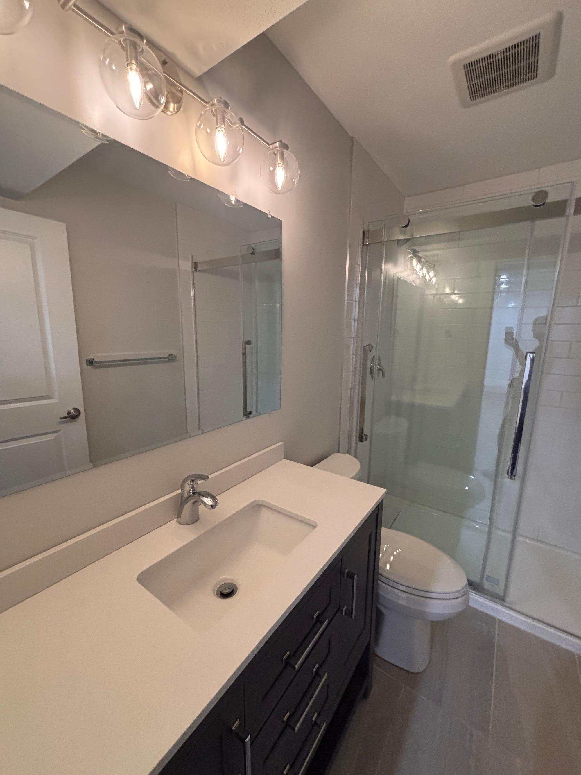 Bathroom after a move out clean, with a clean vanity, mirror and glass shower